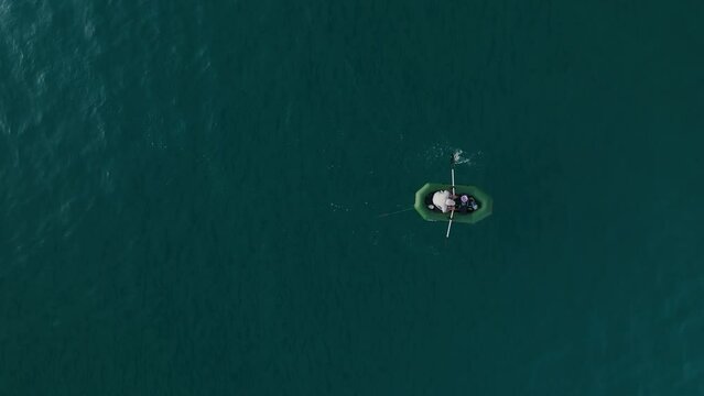 Drone shot, top view fisherman in a grey boat with oars fishing. Beautiful azure water.fv