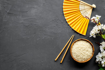 Asian table setting - rice bowl with cherry branch and fan. Top view