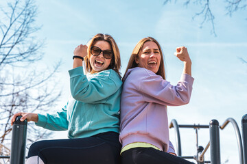 couple of female athletes having fun while climbing on sport metal structure outdoors