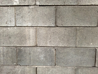 Dirty concrete block wall texture background, front view. Concrete or cobble gray pavement slabs or stones for floor, wall or path. Traditional fence, court, backyard or road paving.