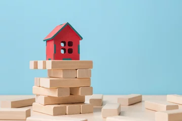 Fotobehang House model on destroying tower of wooden blocks. Risk of owning rental property concept © Vitaliy