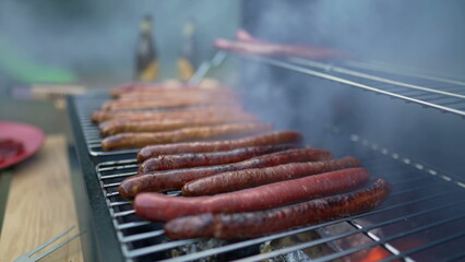 BBQ sausages on grill with smoke. Cooking hot dogs barbecue