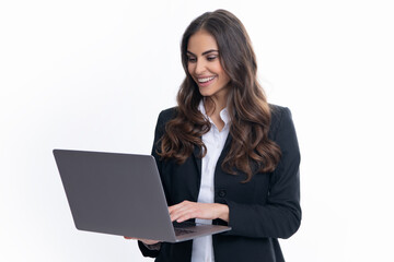 Cheerful business woman standing over grey wall with laptop computer. Portrait of pretty, charming,...