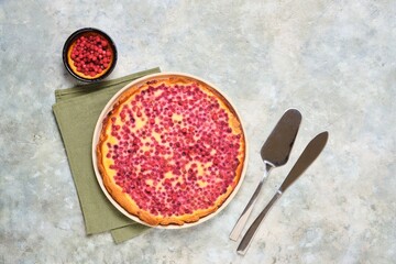 Open pie, shortcrust pastry tart stuffed with cranberries and sour cream filling on a ceramic plate on a gray concrete background. Recipes for pies, tarts.