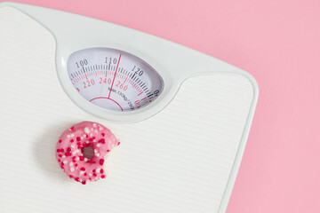 Scales for weighing with pink donut isolated on pink background. Medical starvation. Diet for...