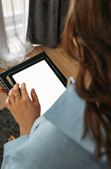 A woman holds a tablet in her hands, on the screen of which there is free space. Mockup.