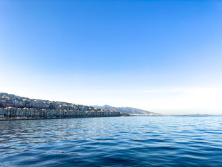 scenic view of the mediterranean sea from İzmir, Türkiye, Konak. Seascape with city and mountain silhouette at left corner, blue sea and sky background