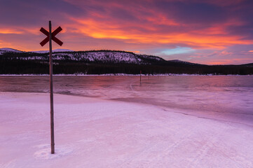 Marked trail over frozen lake at sunrise