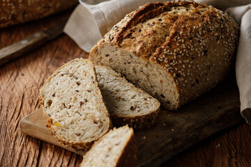 Rustic whole grain bread on a cutting board on a wooden kitchen table