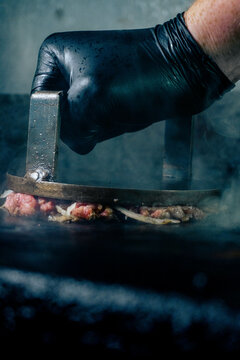 hand of a man smashing an oklahoma burger
