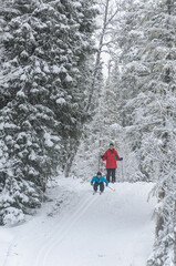 Young cross country skier in front of mother