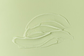 Cosmetic transparent gel serum swatch with bubbles isolated on green background.