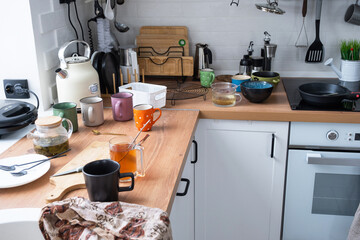A mess in the kitchen, dirty dishes on the table, scattered things, unsanitary conditions. The dishwasher is full, the kitchen is untidy, everyday life - obrazy, fototapety, plakaty