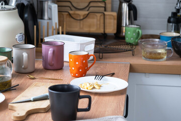 A mess in the kitchen, dirty dishes on the table, scattered things, unsanitary conditions. The dishwasher is full, the kitchen is untidy, everyday life
