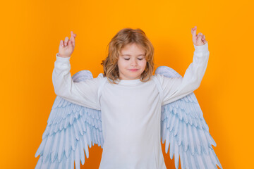 Child angel crossed fingers with lucky and hope, good luck. Beautiful little angel. Isolated studio...