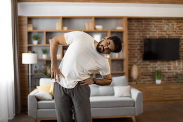 Arabian bearded man dressed in sport clothes holding hands on hips and bending body to sides....