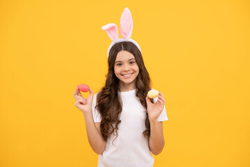 happy child in bunny ears hold eggs on yellow background, happy easter
