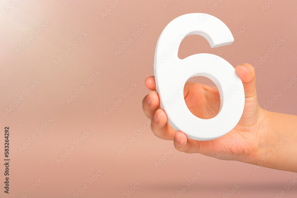 Aufkleber Number six in hand. A hand holds a white number 6 on a red background with copy space. Concept with number six. 6 percent, birthday 6, sixth grade, in sixth grade