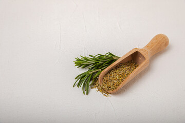 Dried rosemary in wooden spoons and bowl, branches of fresh rosemary on white texture background.Spices and herbs for meat and fish.Recipe.Culinary concept.Organic herbs. Place for text.