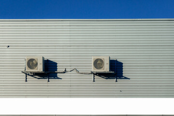 Two old air conditioner hangs on corrugated sheet metal wall of warehouse, storage, store....
