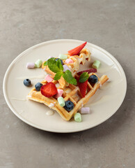 Sweet Belgian waffle with berries and marshmallows. Close-up, isolate.