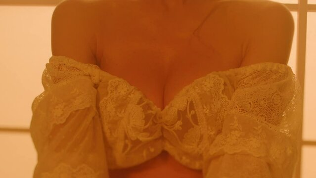 A beautiful young girl showing her breasts covered by an openwork white shirt. Slow motion. Close-up.