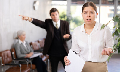 Angry coworker communicating with female inexperienced upset colleague in hallway. Sad woman listening to her annoyed screaming boss. Woman upset due to director s scolding