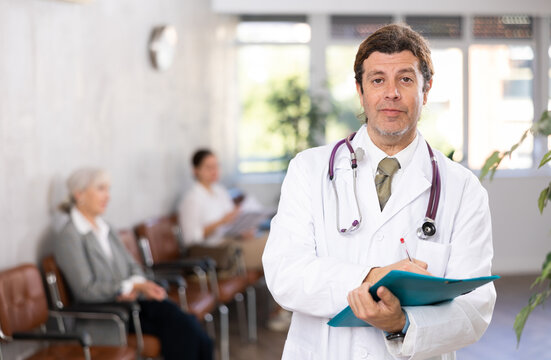 male medical eceptionist affably waiting for patients of clinic in waiting room