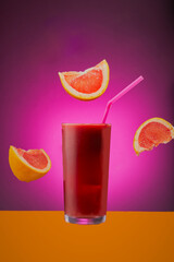 Glass of grapefruit juice isolated on a pink gradient background.