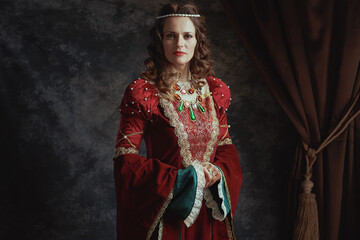 medieval queen in red dress on dark gray background