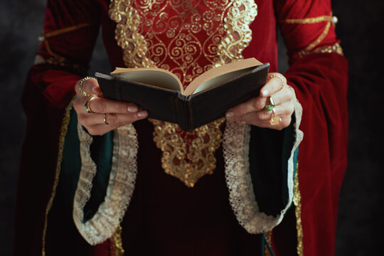 Closeup on medieval queen in red dress with book