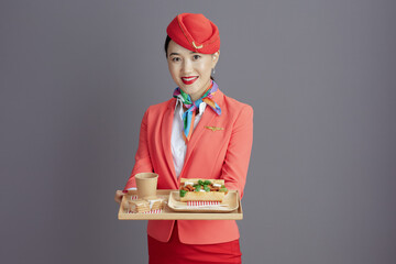 smiling modern asian female flight attendant isolated on grey