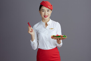 happy asian female stewardess isolated on grey