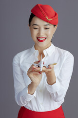 smiling elegant asian female flight attendant isolated on grey