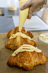 Filling in croissants with cream in a bakery