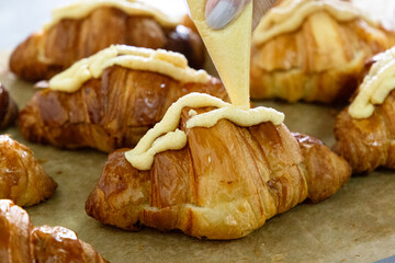 Filling in croissants with cream in a bakery