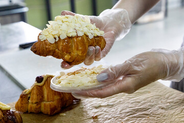 Decorating almond-flavored croissants in a bakery