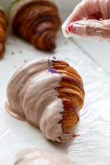 Baker decorating croissant with of violet in a bakery