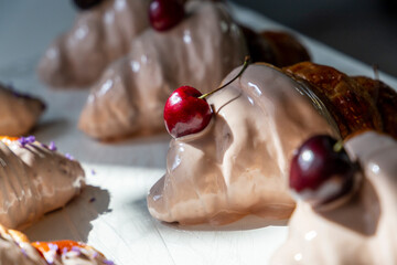 The row of cherry-flavored croissants half covered with white chocolate in a row in a bakery