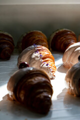 Violet-flavored croissant half covered in white chocolate. Beautifully decorated croissant in the bakery