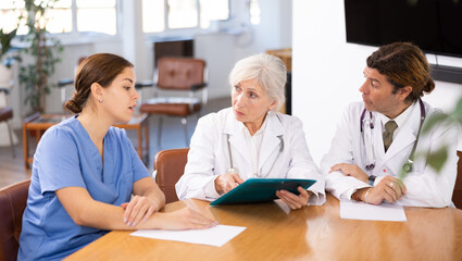 Fototapeta premium Group of professional doctors of different ages sitting at table and discussing diagnosis and treatment of patients during medical council
