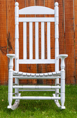 Fairbanks, Alaska, USA - July 27, 2011: White classic lawn wobbling chair set against brown wooden garden fence. Green lawn at bottom
