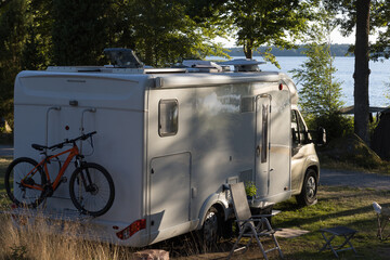 White camper van with bilke on a  camping pitch of a natural campsite in Sweden.	