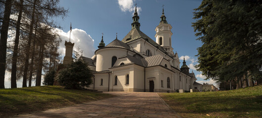 Zabytkowy kościół na tle niebieskiego nieba i białych , puszystych chmur . © Grzegorz