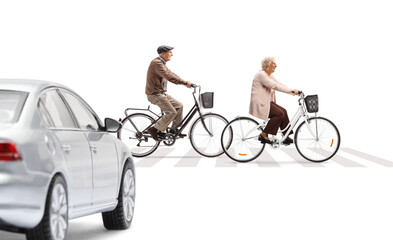 Car waiting and an elderly man and woman crossing with bicycles