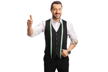 Young tailor with a measuring tape smiling at camera and showing thumbs up