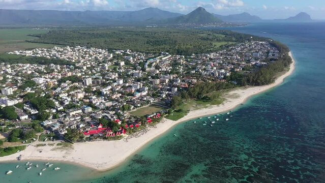 left panning, aerial Landscape video view of Flic en Flac area with cityscape of Flic en Flac and Beaches with boats in Water and Mauritius mountain landscape in the background - footage    