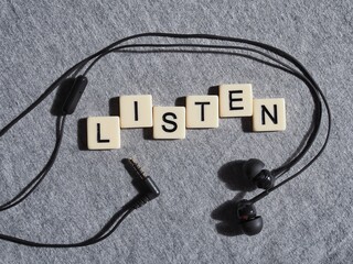 listen written in letters framed with black in ear headphones