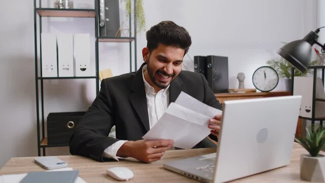 Indian business man open envelope letter, reading it. Career growth advance promotion, bank loan approve, successful admission to monetary award, long-awaited invitation, great news, lottery game win