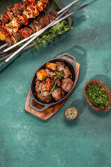 Bbq grilled meat - pork, chicken and vegetable on cast iron pan. Grilled skewers on yellow wooden background. Top view
